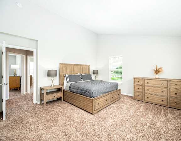 a bedroom with a bed and dressers and a window