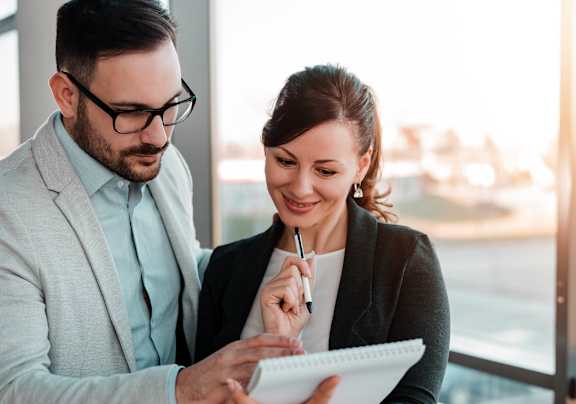 Two people are looking at a notepad together.
