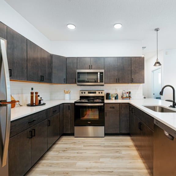 a kitchen with a large island with bar stools and a stainless steel refrigerator