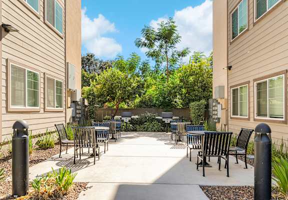 A patio area with chairs and tables surrounded by buildings.