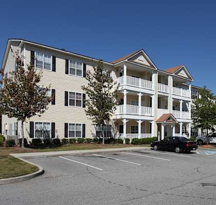 A large apartment complex with a parking lot in front.