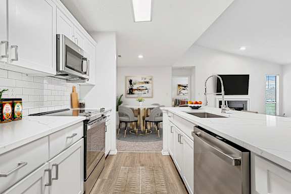 A modern kitchen with white cabinets and stainless steel appliances.