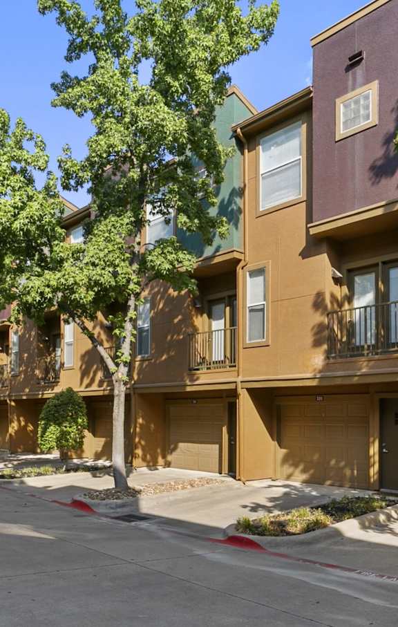 A row of brown apartment buildings with trees in front.
