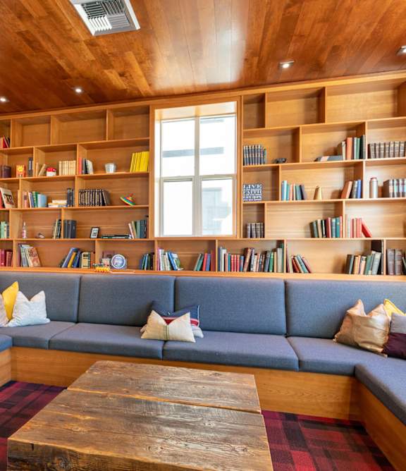A room with a long couch and a bookshelf filled with books.
