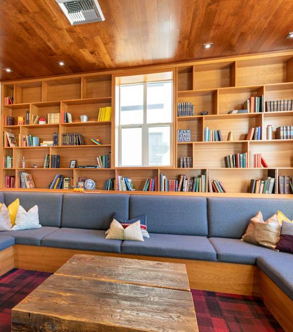 A room with a couch, a coffee table and a bookshelf.