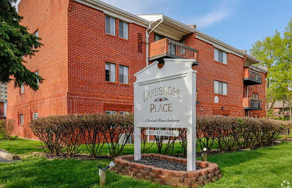 A sign for a place called "Lakeshore Place" stands in front of a red brick building.