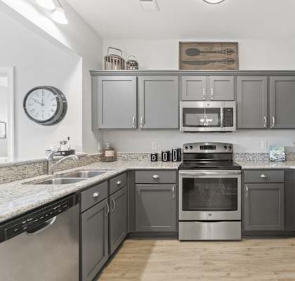 A kitchen with a stainless steel refrigerator and a stove with an oven.