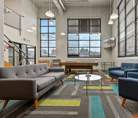 A modern living room with a grey sofa, blue armchair, and a coffee table.