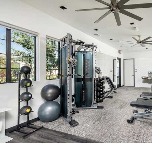 A spacious home gym with a variety of equipment including a treadmill, weights, and a bench press. at Grandstone at Sunrise, Peoria, AZ, 85383