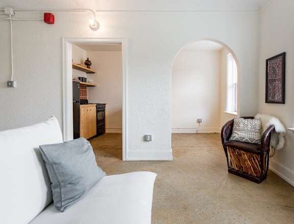 a living room with a couch and a chair and a door to a kitchen