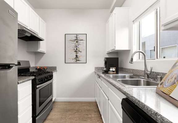 A modern kitchen with a stove, sink, and cabinets.