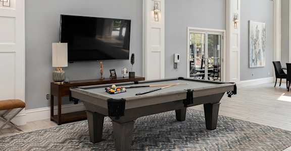 A pool table with a television in the background.