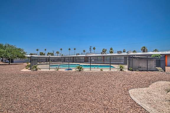 a yard with a pool and a fence in front of a building