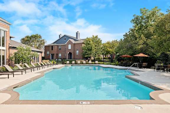 A large swimming pool surrounded by lounge chairs and trees.