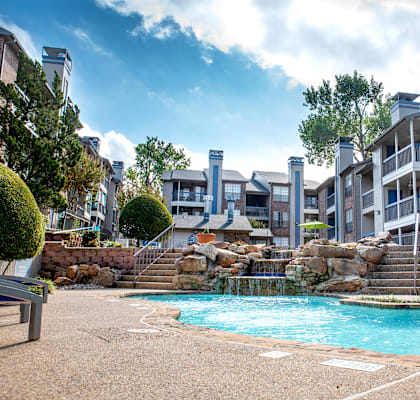 a swimming pool with a waterfall in front of an apartment building at Infinity on the Mark, Dallas, TX, 75243
