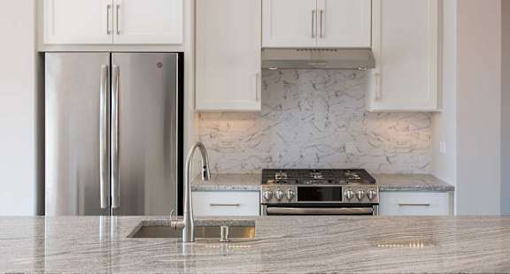 a kitchen with marble counter tops and a stainless steel refrigerator