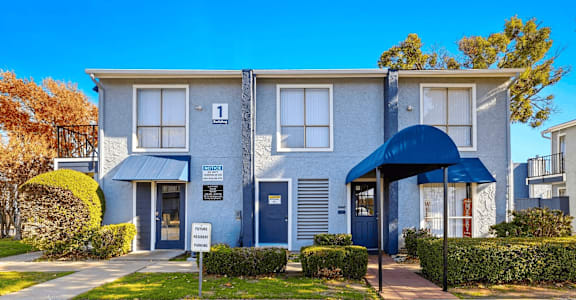 A blue and white two-story building with a blue awning and a sign on the front.