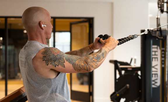 A man with a tattoo on his arm is working out in a gym.