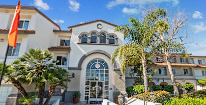 the front facade of a villa with palm trees and a flag