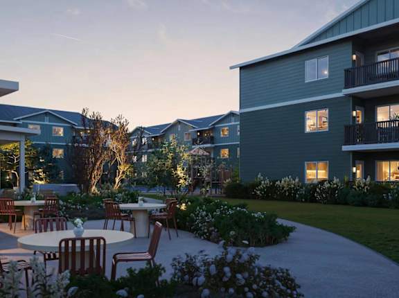 A patio area with tables and chairs is surrounded by apartment buildings.