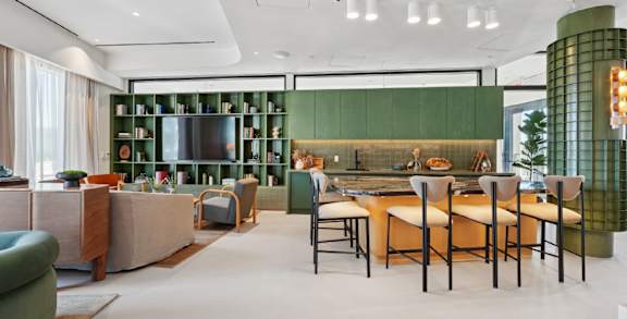 A modern living room with a green bookshelf and a dining table set for four.
