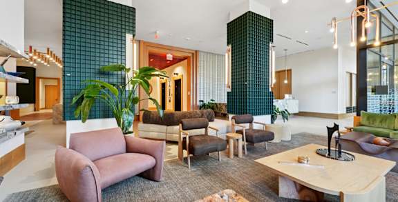 A modern living room with a variety of seating options and a green tiled wall.