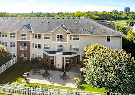 A large apartment complex with a fenced in yard and a tree.
