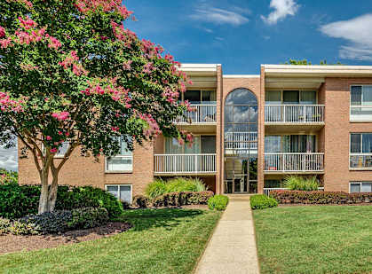 A brick apartment building with a green lawn in front.