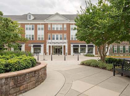 a large building with trees and a bench in front of it