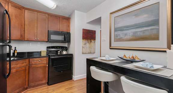 A kitchen with a black counter top and white chairs.