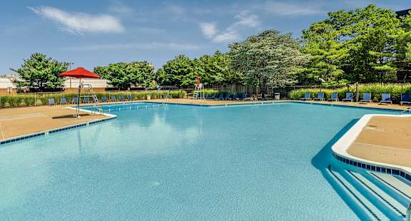 A large swimming pool with a red roof and trees in the background.