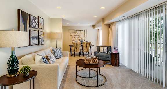A living room with a white sofa, a green vase, and a wooden coffee table.