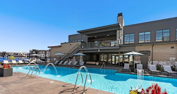 A large outdoor swimming pool with a slide and lounge chairs.