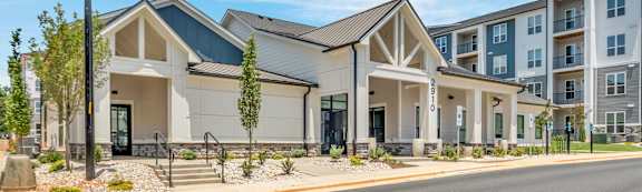 A modern building with a white and grey exterior is surrounded by a well-maintained landscaped area.