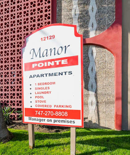 A sign for the Maror Apartments is displayed in front of a building.