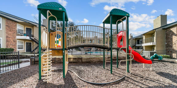 a playground with a slide and swings at an apartment complex