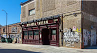A building with a red door and graffiti on the wall.