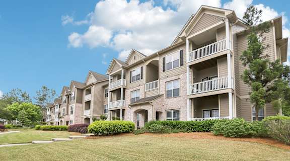 Apartment building with balconies and green lawn in front.