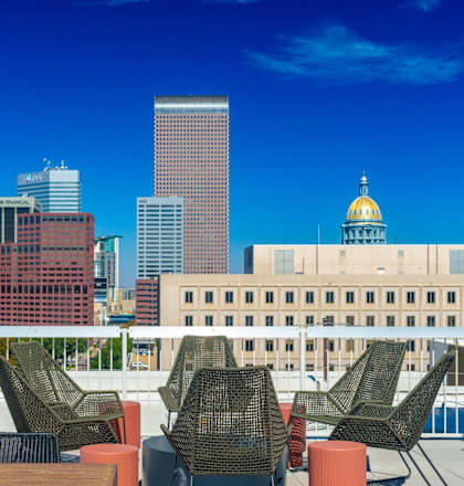 A rooftop patio with chairs and a table overlooking a city skyline.