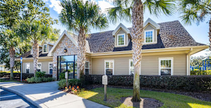 A house with a driveway and palm trees in front.