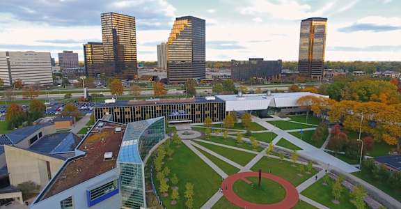 A cityscape with a mix of modern and traditional architecture, featuring a large open space with a fountain in the center.