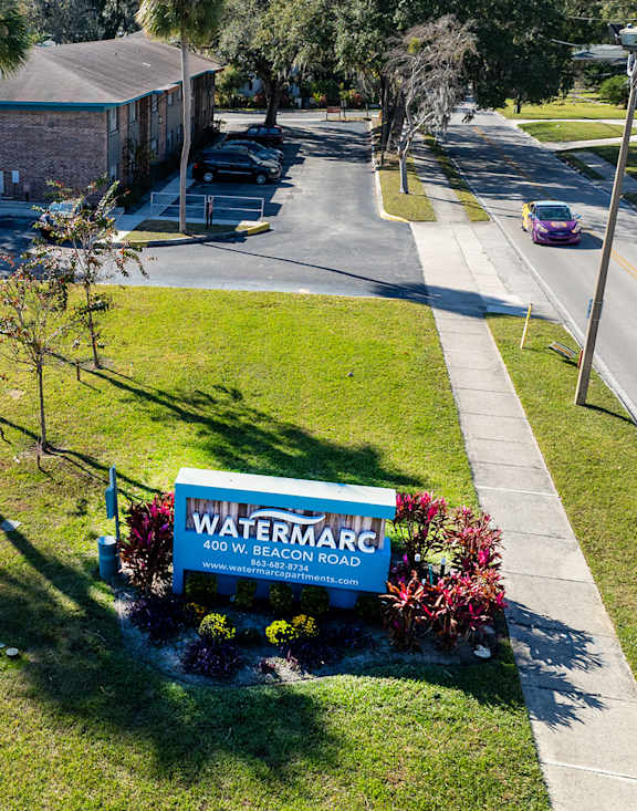 Watermarc Apartments blue monument sign surrounded by grass and brick apartments