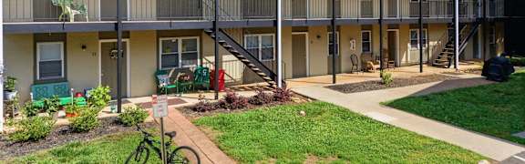 Apartment complex with greenery and a bicycle parked in front.