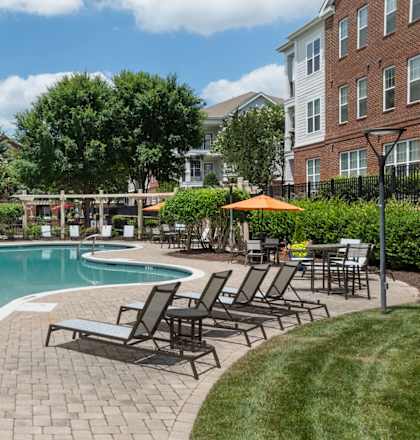 a swimming pool with chairs and umbrellas in front of a building