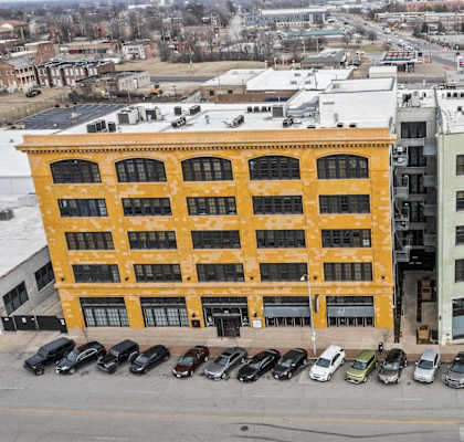 A yellow building is in the middle of a parking lot.