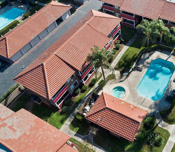 A swimming pool is surrounded by a red tiled roof.