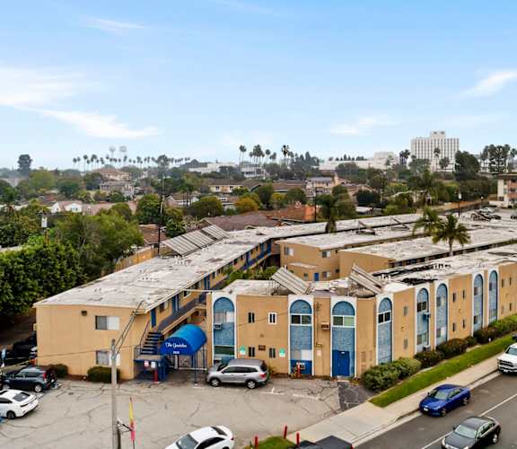 A parking lot with cars and a yellow building with blue doors.