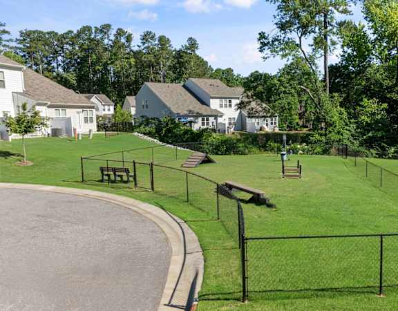 a park with a fenced in area and houses in the background