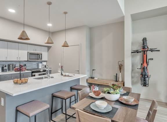 A modern kitchen with a dining table set for two.