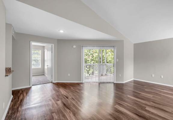 A spacious room with wooden floors and a large window.